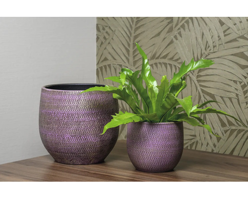 Twee decoratieve plantenbakken op een tafel, waarvan één met een plant.