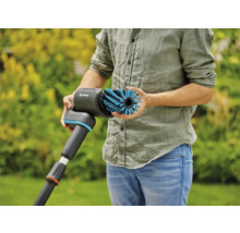 Een persoon houdt een Gardena borstel vast voor het reinigen van oppervlakken buitenshuis