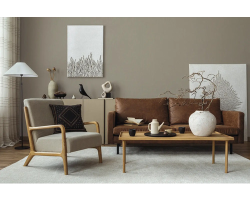Woonkamer met leren bank, fauteuil, houten tafel en decoratieve elementen voor een stijlvolle inrichting
