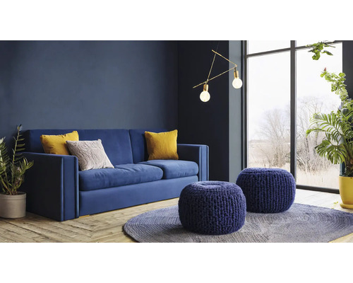 Woonkamer met blauwe bank, sierkussens, ronde hockers en kamerplanten