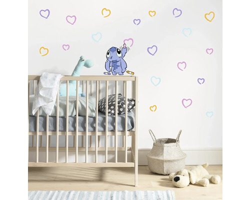 Kinderkamer met kinderbed, wasmand, speelgoed en muursticker met harten en Stitch motief