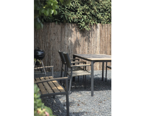 Tuinscene met barbecue, eettafel en stoelen voor een houten schutting