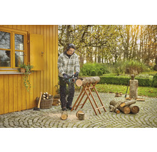 Man zaagt hout met een kettingzaag in de tuin.