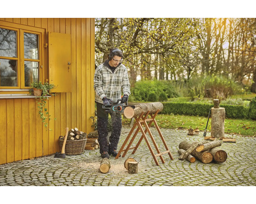 Man zaagt hout met een kettingzaag in de tuin.