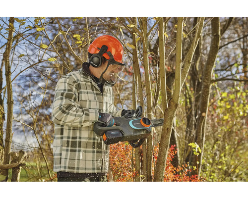 Man met veiligheidshelm en accu kettingzaag snoeit boom