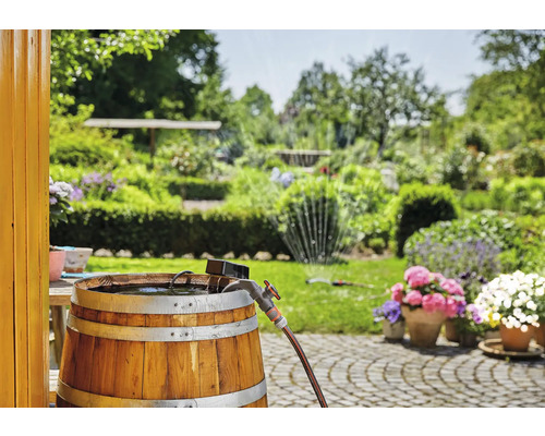 Houten vat als regenton met kraan en tuinslang in de tuin