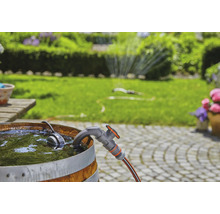 Tuinscene met regenton, kraan en tuinslang voor een groen gazon