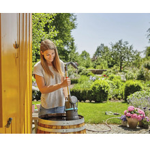 Vrouw bedient regentonpomp in de tuin voor irrigatie.