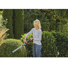 Vrouw snoeit heg met heggenschaar in de tuin.