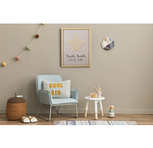 Gedecoreerde kinderkamer met stoel, bijzettafel, speelgoed en wanddecoraties.
