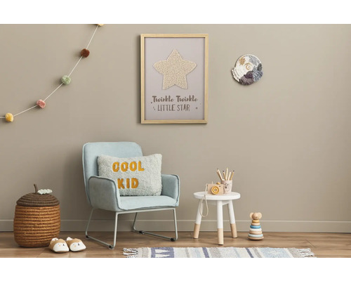 Gedecoreerde kinderkamer met stoel, bijzettafel, speelgoed en wanddecoraties.