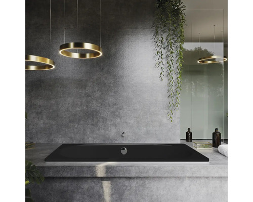 Badkamer met zwart ligbad, ronde plafondlampen en betonnen muur