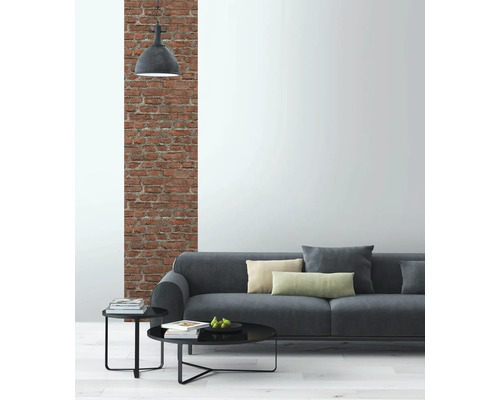 Woonkamer met grijze bank, bijzettafels en bakstenen muur