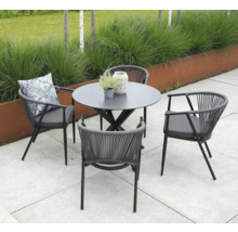 Tuinopstelling met ronde tafel en vier stoelen met armleuningen en kussens.