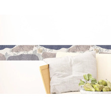 Wandbordüre met plantenmotief boven een fauteuil met kussens en een schaal met peren