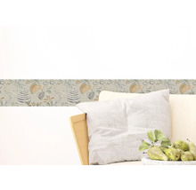 Wandborder met bloemmotief boven een fauteuil met kussens en een schaal met peren