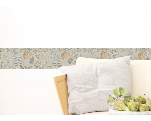 Wandborder met bloemmotief boven een fauteuil met kussens en een schaal met peren