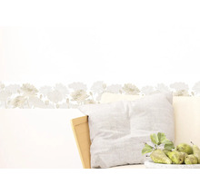 Wandbordüre met bloemmotief boven een kussen en een schaal met peren.