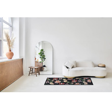 Lichte ruimte met bank, spiegel en deurmat met bloemmotief.