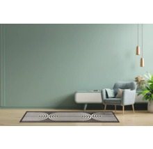 Woonkamer met fauteuil, vloerkleed en bijzettafel.