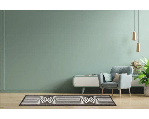 Woonkamer met fauteuil, vloerkleed en bijzettafel.