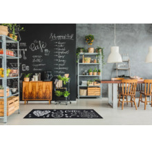 Scene van een eetkamer met krijtbordmuur, rekken en een vloermat met koffiemotieven.