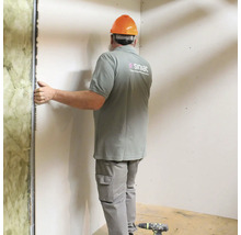Een vakman installeert een gipsplatenwand met isolatie en metalen frame.