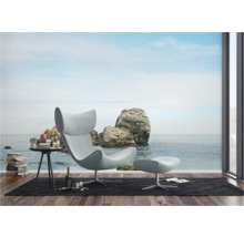 Woonkamer met fauteuil, voetenbank en fotobehang met rotsen aan zee