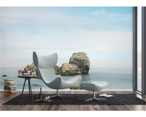 Woonkamer met fauteuil, voetenbank en fotobehang met rotsen aan zee