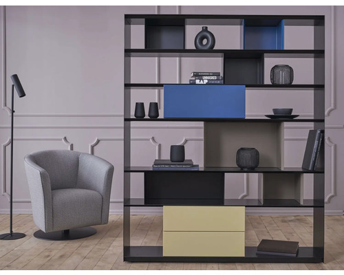 Woonkamer met boekenrek, fauteuil en vloerlamp