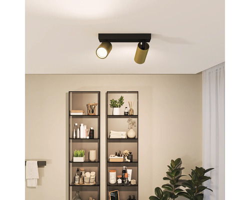 Tweearmige plafondlamp in badkamer met schappen.