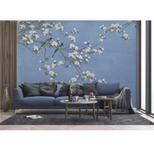 Woonkamer met een blauwe bank voor een behang met vogel- en bloemmotief