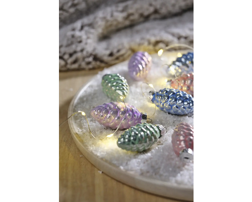 Decoratieve dennenappels met lichtketting op een bord met kunstsneeuw