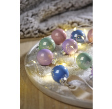 Veelkleurige kerstballen met lichtketting op een bord