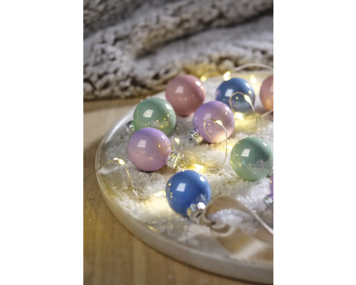 Veelkleurige kerstballen met lichtketting op een bord