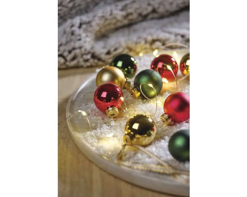 Decoratieve kerstballen op een bord met kunstsneeuw en lichtjes