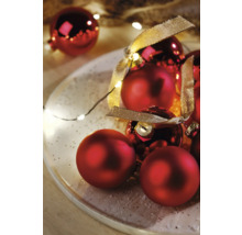 Rode kerstballen met lint op een bord met lichtslinger