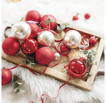 Decoratieve kerstballen in rood en zilver op een houten dienblad.