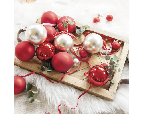 Decoratieve kerstballen in rood en zilver op een houten dienblad.