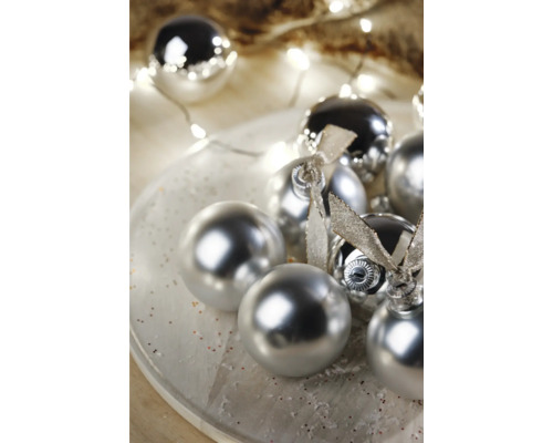 Decoratieve kerstballen met glanzend oppervlak en linten op een bord