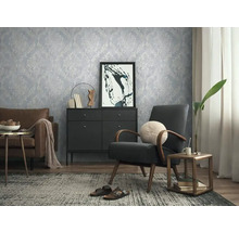 Woonkamer met gedessineerd behang, fauteuil en ladekast