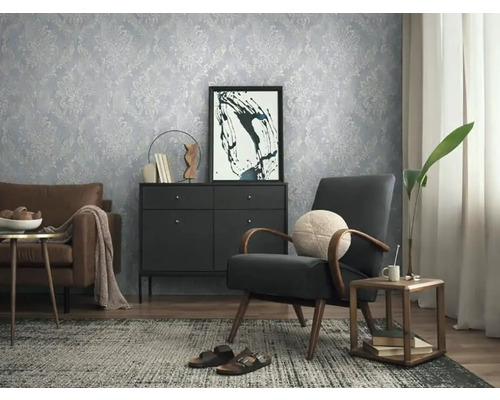 Woonkamer met gedessineerd behang, fauteuil en ladekast