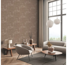 Woonkamer met patroonbehang, bank, fauteuil en bijzettafels.