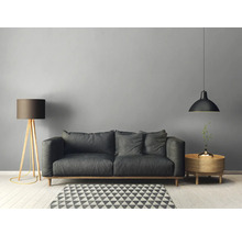 Woonkamer met bank, vloerlamp, hanglamp en bijzettafel op een geometrisch tapijt