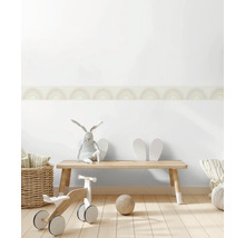 Kinderkamer met houten bank, loopfiets, speelgoed en muurborduur met regenboogpatroon