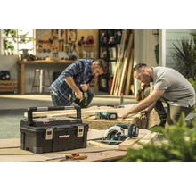 Werkplaatsopname met gereedschapskist, handzaag en twee ambachtslieden aan het werk