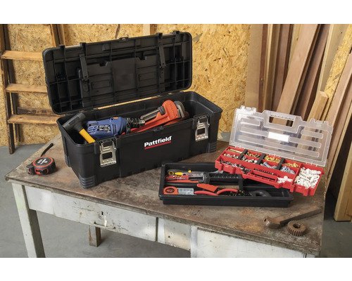 Geopende gereedschapskist met gereedschap en assortimentsdoos op een tafel.