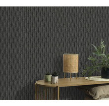 Close-up van een muur met een gestructureerd behang, een tafel met een lamp en planten