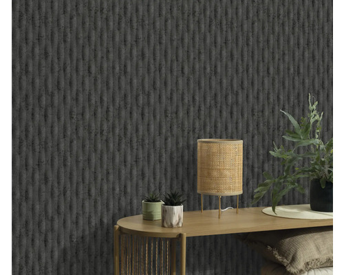 Close-up van een muur met een gestructureerd behang, een tafel met een lamp en planten