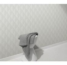 Lichte wand met geometrisch patroon en kruk met deken